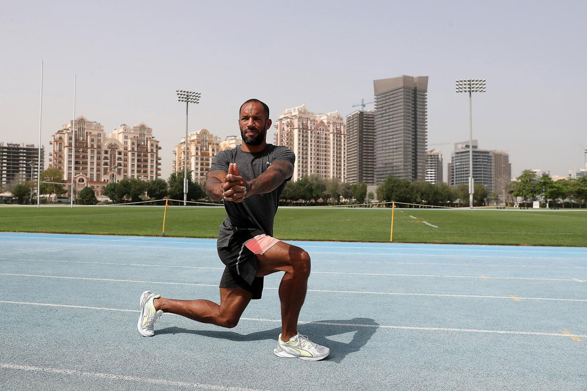 The coach is stretching on a running track.